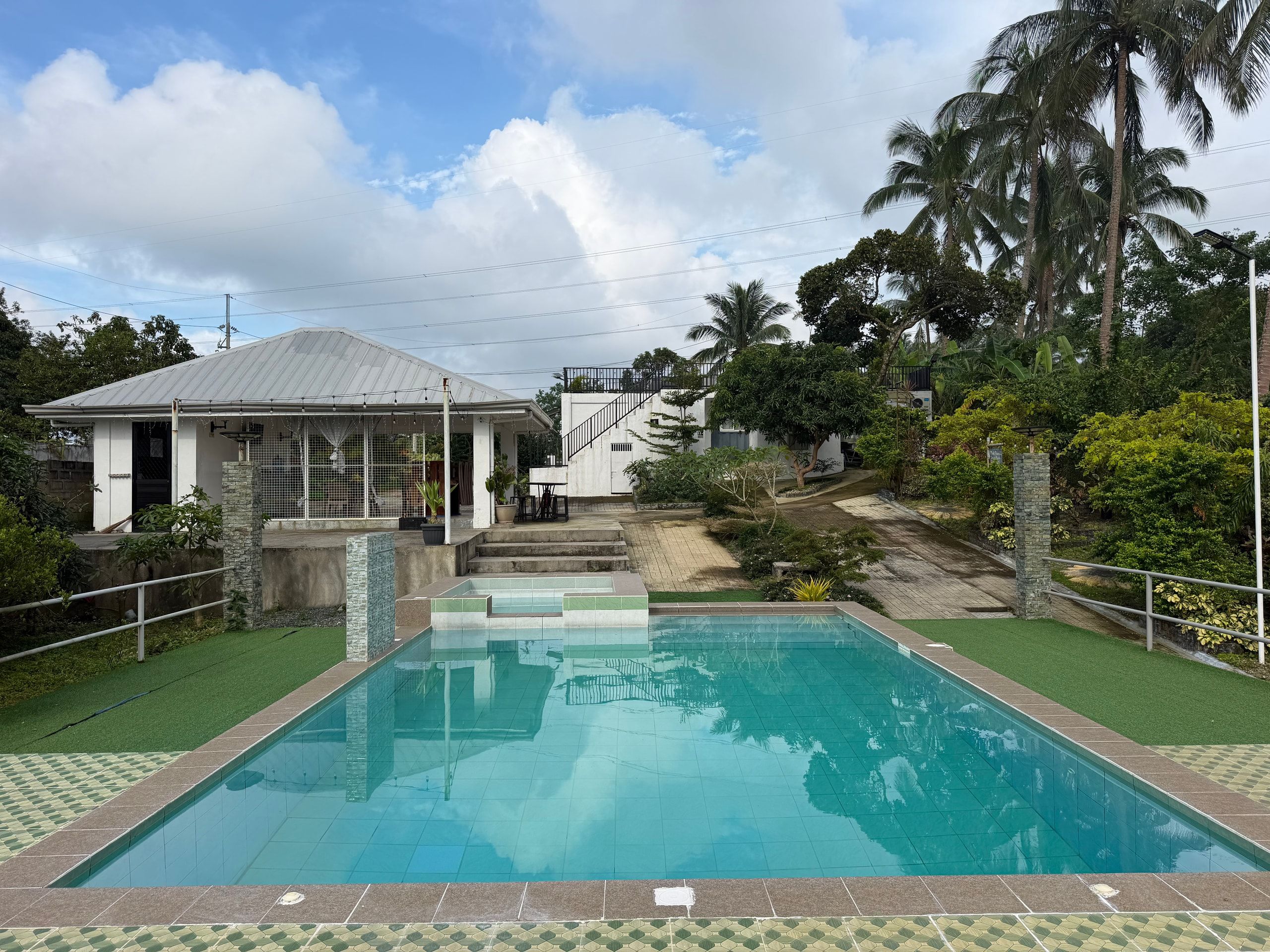 The private pool and raised kiddie pool at Casa Pabugnaw, with the dining pavilion and the main house behind under a blue sky