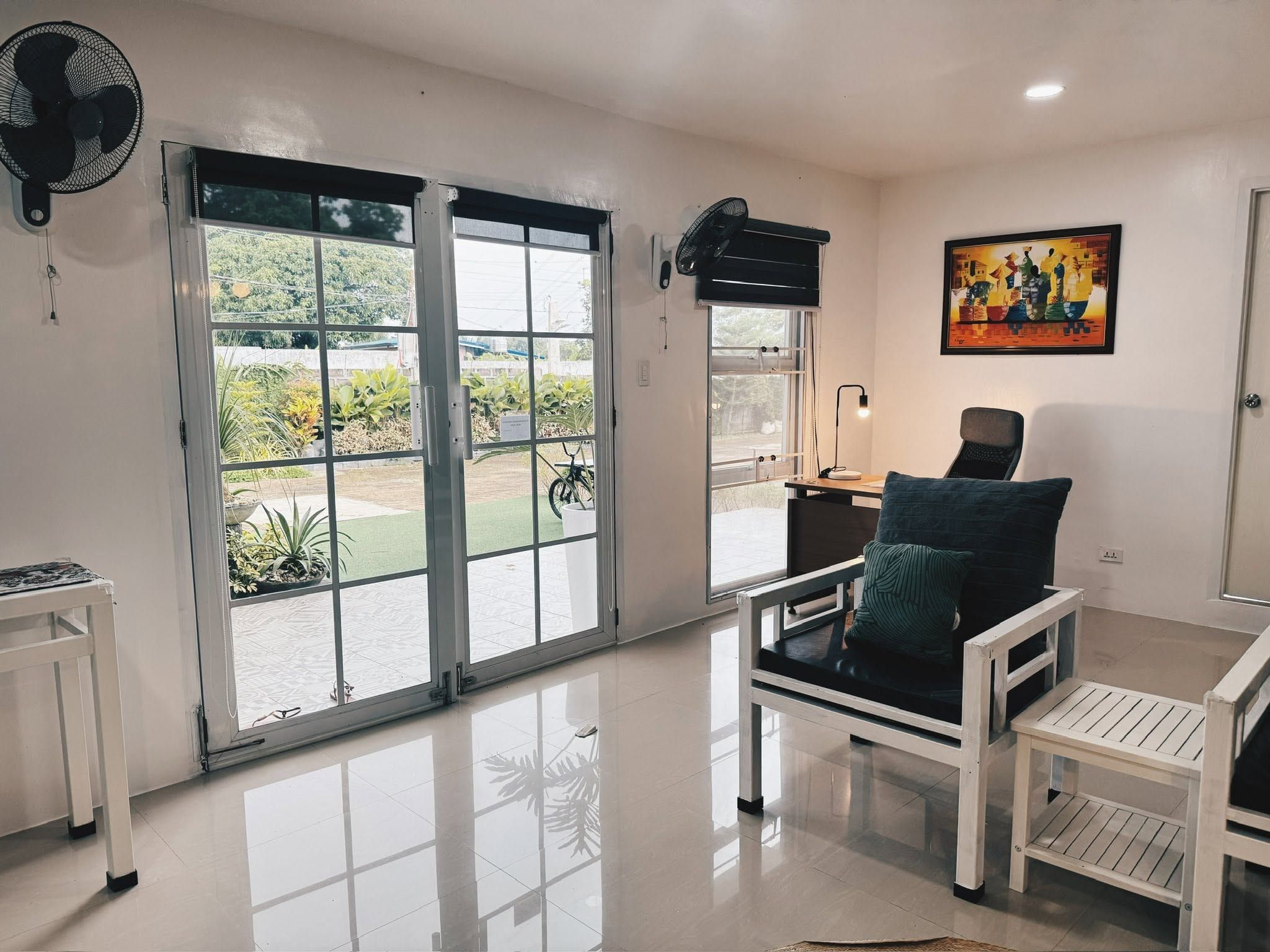 Sitting area with white-framed chairs beside glass French doors that open onto the lawn